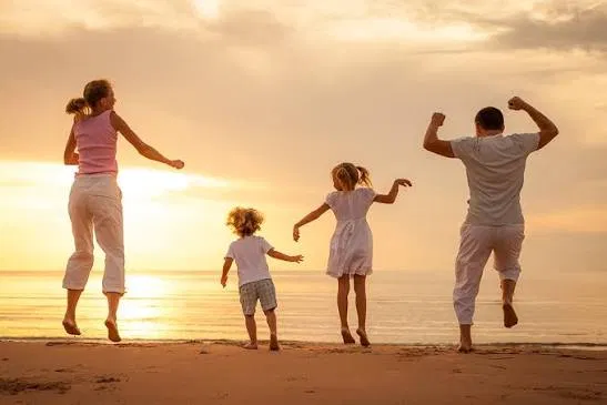 A family jumping for joy on the beach at sunset